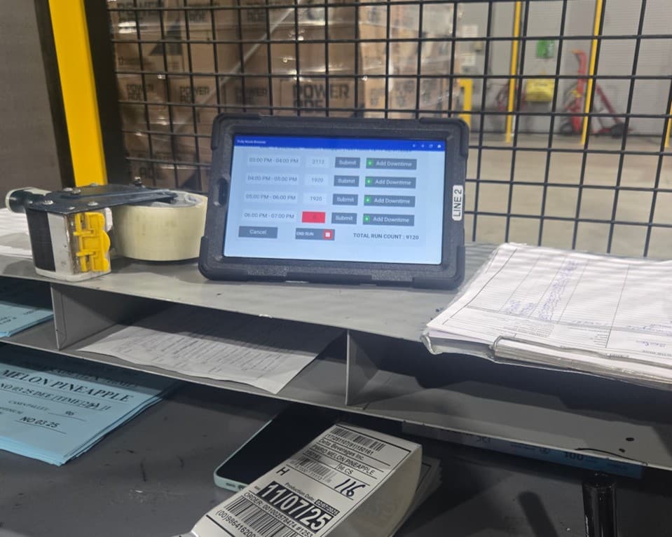 A line operator using a tablet on the Delta Beverages production floor to log production data.